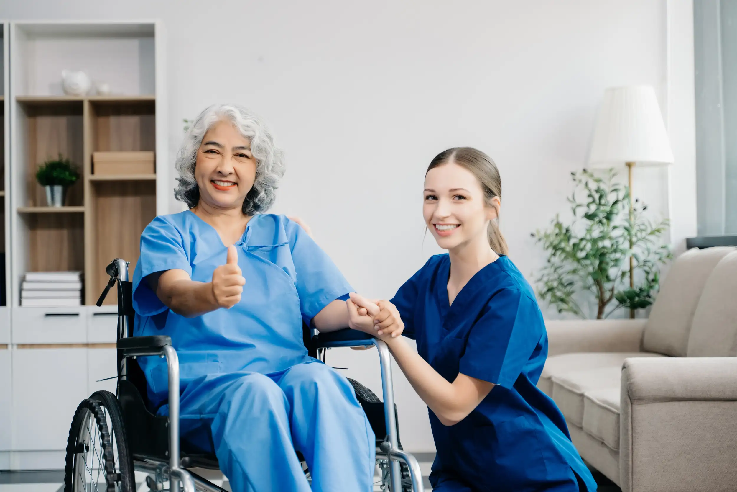 An elderly woman in a wheel-chair with her nurse beside.