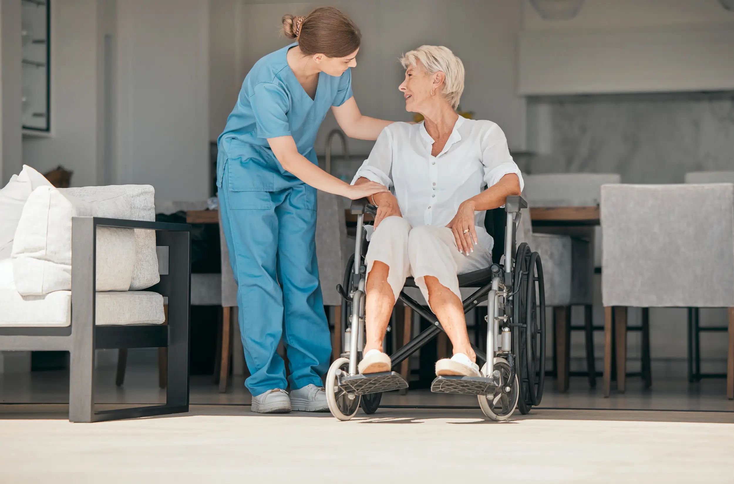 An senior woman in a wheelchair with a nurse assisting her.